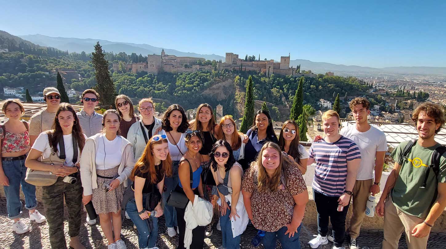 A group of students smiling at a scenic viewpoint of the Albaicín district in Granada, Spain